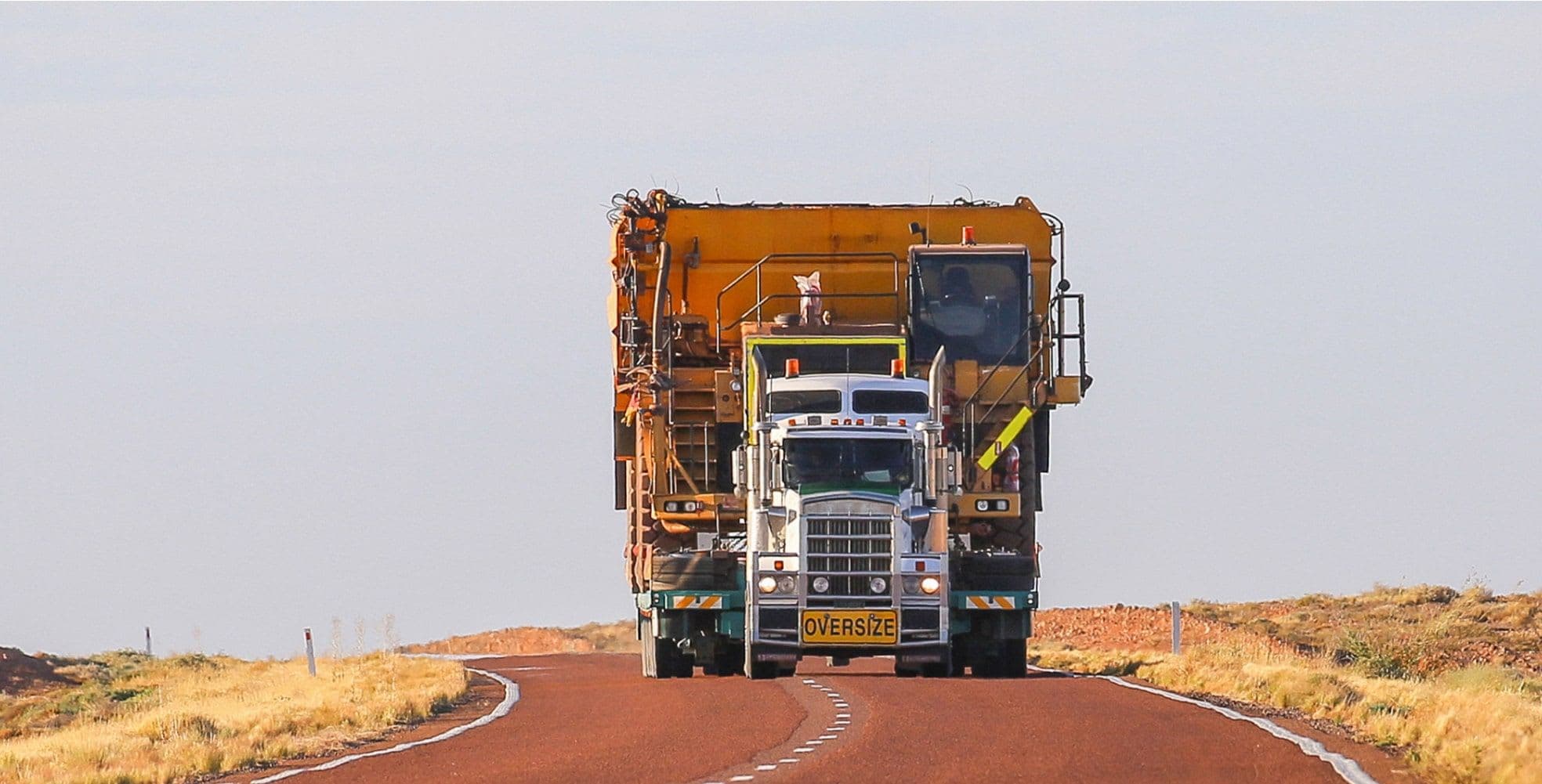 A large truck driving down a desert road with an oversized load