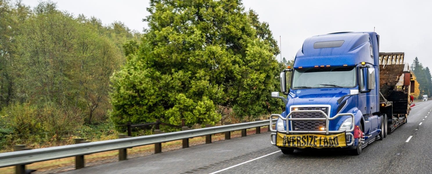 A truck driving down an interstate with an oversize load